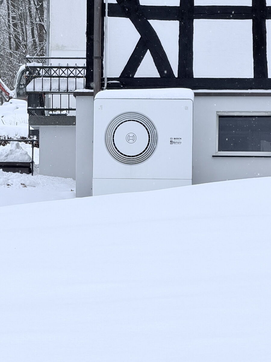 Bosch-Wärmepumpe im Schnee vor einem Fachwerkhaus