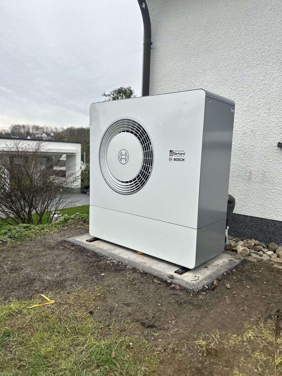 Bosch-Luft-Wasser-Wärmepumpe auf Betonfundament an der Hauswand eines Einfamilienhauses